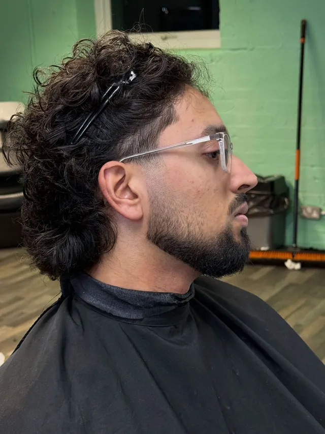 A curly mullet with a shaped beard